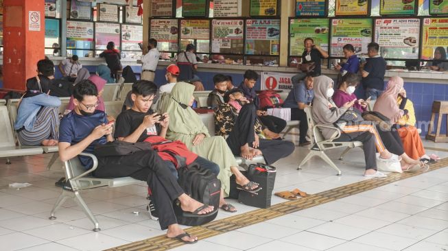Calon pemudik menunggu di Kampung Rambutan, Jakarta Timur, Senin (18/4/2022). [Suara.com/Alfian Winanto]