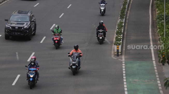 Sejumlah kendaraan melintas di samping jalur khusus sepeda di Jalan Jenderal Sudirman, Jakarta, Senin (18/4/2022). [Suara.com/Angga Budhiyanto]