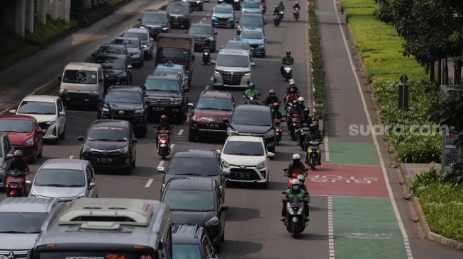 Sejumlah kendaraan melintas di samping jalur khusus sepeda di Jalan Jenderal Sudirman, Jakarta, Senin (18/4/2022). [Suara.com/Angga Budhiyanto]