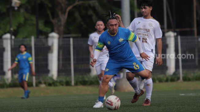 Pemain Selebritis FC Augie Fantinus berusaha melewati lawan saat mengikuti sesi latihan di Lapangan ABC, Kompleks Gelora Bung Karno, Jakarta, Senin (18/4/2022). [Suara.com/Angga Budhiyanto]