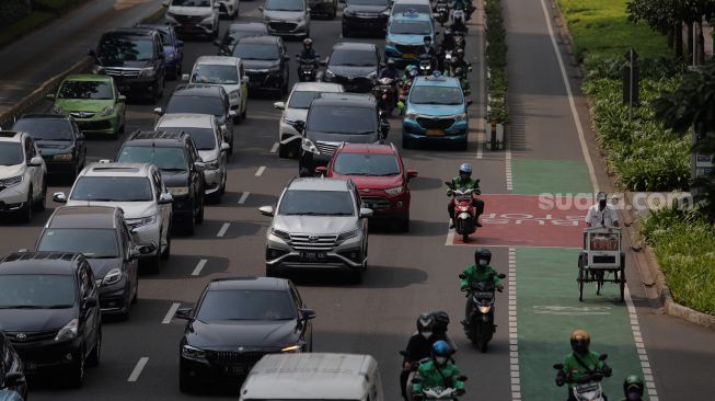 Seorang pedagang melintasi jalur khusus sepeda di Jalan Jenderal Sudirman, Jakarta, Senin (18/4/2022). [Suara.com/Angga Budhiyanto]