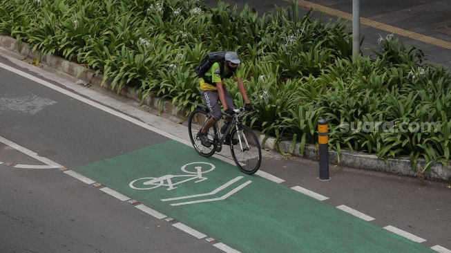 Pesepeda melintasi jalur khusus sepeda di Jalan Jenderal Sudirman, Jakarta, Senin (18/4/2022). [Suara.com/Angga Budhiyanto]