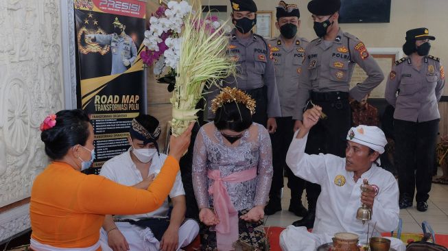 Anggota Polisi berjaga di dekat tahanan kasus narkotika I Wayan Bawa Kartika bersama pasangannya saat melakukan upacara pernikahan secara adat Bali di lobi Polresta Denpasar, Bali, Senin (18/4/2022). ANTARA FOTO/Nyoman Hendra Wibowo
