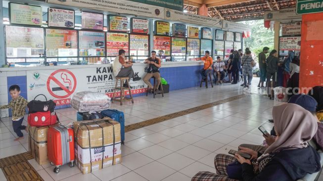 Calon pemudik menunggu di Kampung Rambutan, Jakarta Timur, Senin (18/4/2022). [Suara.com/Alfian Winanto]