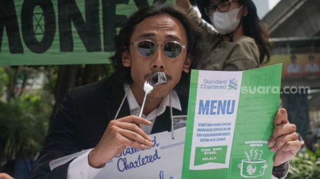 Sejumlah aktivis melakukan aksi teatrikal fine dining restaurant di depan kantor Standard Chartered di kawasan Setiabudi, Jakarta Selatan, Selasa (19/4/2022). [Suara.com/Alfian Winanto]