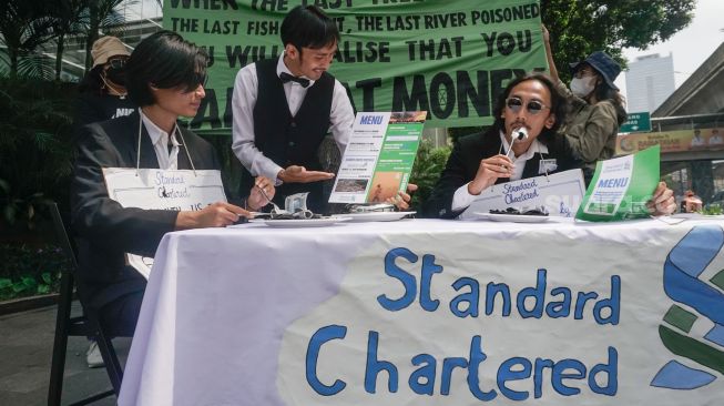 Sejumlah aktivis melakukan aksi teatrikal fine dining restaurant di depan kantor Standard Chartered di kawasan Setiabudi, Jakarta Selatan, Selasa (19/4/2022). [Suara.com/Alfian Winanto]