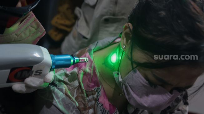 Petugas menghapus tinta tato dengan menggunakan laser saat kegiatan hapus tato gratis di Kantor Sekretariat DPP Forum Ulama Habaib (Fuhab), Jakarta, Selasa (19/4/2022). [Suara.com/Angga Budhiyanto]