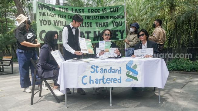 Sejumlah aktivis melakukan aksi teatrikal fine dining restaurant di depan kantor Standard Chartered di kawasan Setiabudi, Jakarta Selatan, Selasa (19/4/2022). [Suara.com/Alfian Winanto]