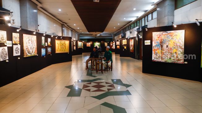 Pengunjung melihat Pameran Kaligrafi Kontemporer Internasional di Masjid Raya Jakarta Islamic Center, Jakarta Utara, Senin (18/4/2022). [Suara.com/Alfian Winanto]