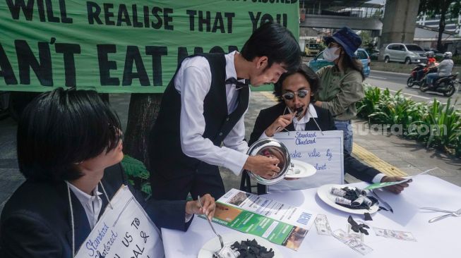 Sejumlah aktivis melakukan aksi teatrikal fine dining restaurant di depan kantor Standard Chartered di kawasan Setiabudi, Jakarta Selatan, Selasa (19/4/2022). [Suara.com/Alfian Winanto]