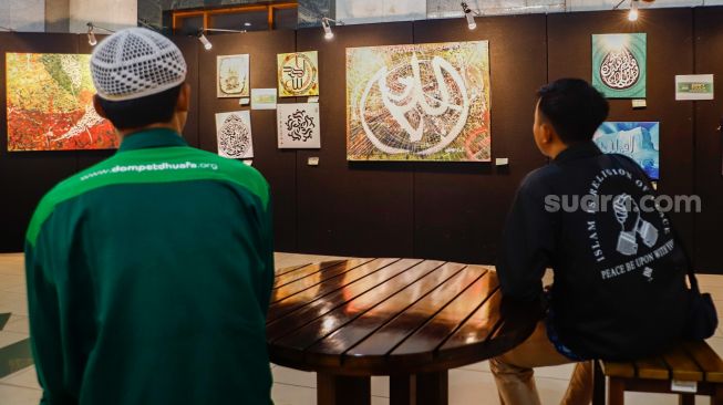 Pengunjung melihat Pameran Kaligrafi Kontemporer Internasional di Masjid Raya Jakarta Islamic Center, Jakarta Utara, Senin (18/4/2022). [Suara.com/Alfian Winanto]