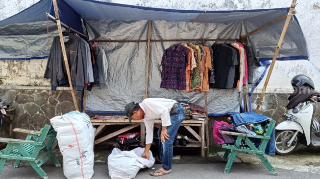 Para pelapak barang pakaian bekas menata dagangannya di Gang 1, Jalan Jenderal Suprapto, Purwokerto, Rabu (20/4/2022). [Suara.com/Anang Firmansyah]