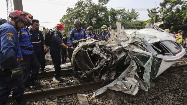 Sejumlah petugas melakukan evakuasi mobil yang tertabrak KRL di kawasan Rawageni, Cipayung, Depok, Jawa Barat, Rabu (20/4/2022).  ANTARA FOTO/Asprilla Dwi Adha