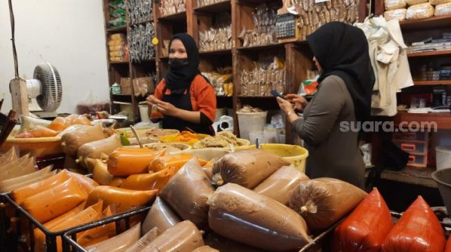 Seorang pegawai membungkus satu racikan bumbu rendang kepada pelanggan di lapak milik Tuti  Maryati di Pasar Beringharjo, Kota Jogja, Selasa (19/4/2022). - (SuaraJogja.id/Muhammad Ilham Baktora)