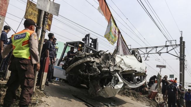 Sejumlah petugas melakukan evakuasi mobil yang tertabrak KRL di kawasan Rawageni, Cipayung, Depok, Jawa Barat, Rabu (20/4/2022).  ANTARA FOTO/Asprilla Dwi Adha