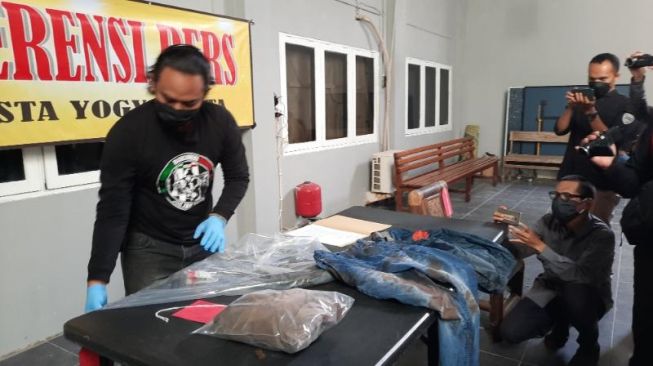 Petugas polisi merapikan barang bukti kasus pembunuhan di Wirobrajan oleh pelaku W saat konferensi pers di Mapolresta Yogyakarta,  Rabu (20/4/2022). [Muhammad Ilham Baktora / SuaraJogja.id]