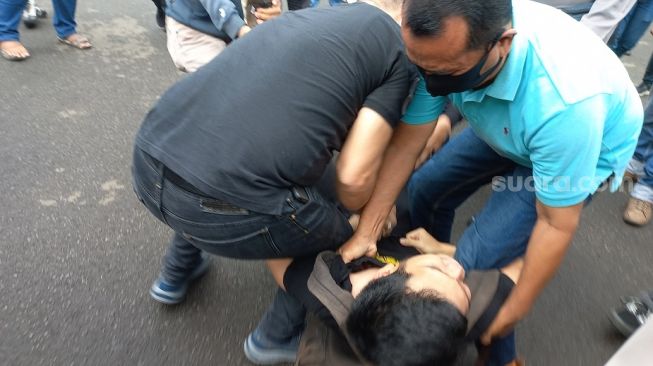 Aparat kepolisian menangkap seorang pria yang diduga sebagai provokator saat aksi unjuk rasa Aliansi Mahasiswa Indonesia (AMI) di kawasan Patung Kuda Jakarta Pusat, Kamis (21/4/2022). (Suara.com/Yaumal)