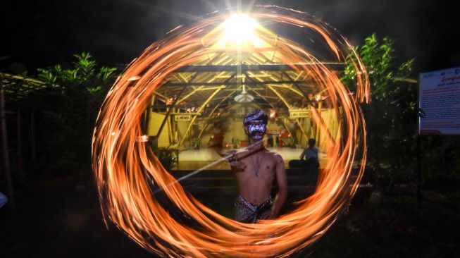 Seorang warga melakukan atraksi api pada acara Purnacandra di Kampung Batara, Papring Kalipuro, Banyuwangi, Jawa Timur, Rabu (20/4/2022) malam.  ANTARA FOTO/Budi Candra Setya