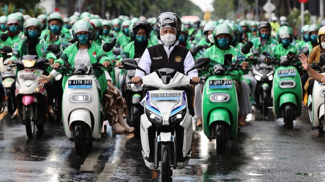 Gubernur Jawa Timur Khofifah Indar Parawansa (tengah) mengendarai motor listrik GESITS saat mengikuti konvoi bersama 100 pengemudi ojek daring perempuan di Surabaya, Jawa Timur, Kamis (21/4/2022).  ANTARA FOTO/Trisnadi