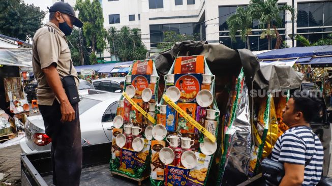 Pedagang merapikan parcel lebaran di Pasar Kembang Cikini, Jakarta Pusat, Kamis (21/4/2022). [Suara.com/Alfian Winanto]