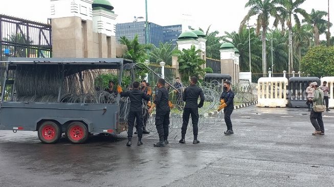 Polisi saat memasang kawat berduri di sekitar gedung DPR RI jelang aksi demonstrasi mahasiswa pada Kamis 21 April 2022. (suara.com/bagaskara)