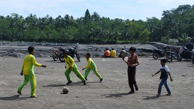 Siswa SDN Jugosari 3 bermain bola di pinggir Sungai Regoyo, Desa Jugosari, Candipuro, Lumajang, Jawa Timur.