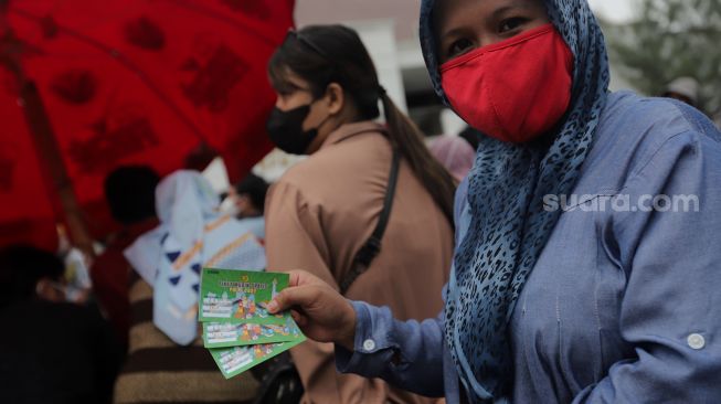 Warga menunjukkan tiket mudik gratis angkutan Lebaran di Polda Metro Jaya, Jakarta, Sabtu (23/4/2022). [Suara.com/Angga Budhiyanto]