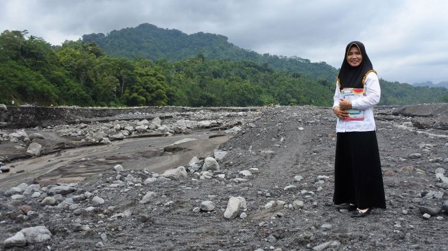 Guru SDN Jugosari 03 Lilik Kusnilawati berpose di Sungai Regoyo di Dusun Sumberlangsep, Desa Jugosari, Candipuro, Lumajang, Jawa Timur.