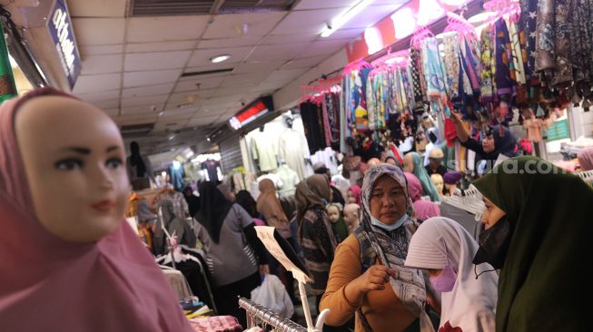 Pengunjung melihat pakaian di Pasar Tanah Abang, Jakarta, Sabtu (23/4/2022). [Suara.com/Angga Budhiyanto]