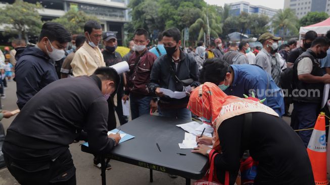 Warga mengisi formulir untuk mendaftar mudik gratis angkutan Lebaran di Polda Metro Jaya, Jakarta, Sabtu (23/4/2022). [Suara.com/Angga Budhiyanto]