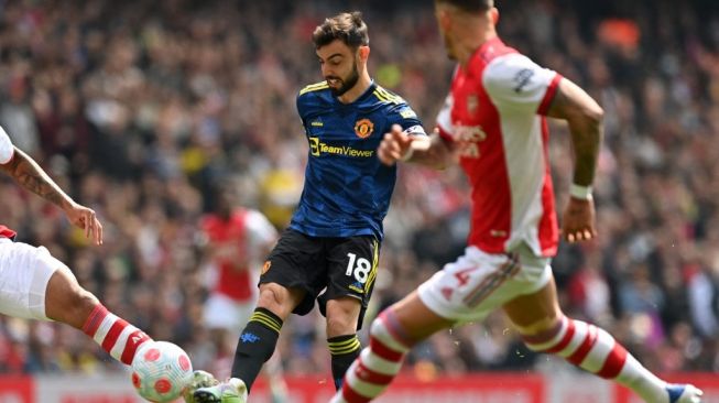 Pemain tengah Manchester United asal Portugal Bruno Fernandes (tengah) melepaskan tembakan yang diblok pemain lawan selama pertandingan Liga Inggris antara Arsenal vs Manchester United di Stadion Emirates, London pada 23 April 2022.Glyn KIRK / AFP.