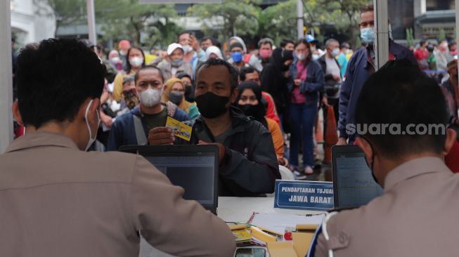 Polisi memberikan tiket mudik gratis angkutan Lebaran kepada warga di Polda Metro Jaya, Jakarta, Sabtu (23/4/2022). [Suara.com/Angga Budhiyanto]