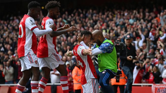 Gelandang Arsenal Granit Xhaka (tengah) melakukan selebrasi dengan striker Arsenal Alexandre Lacazette (kanan) usai mencetak gol saat pertandingan sepak bola Liga Premier Inggris antara Arsenal dan Manchester United di Stadion Emirates, London, Inggris, Sabtu (23/4/2022). [Glyn KIRK / AFP]
