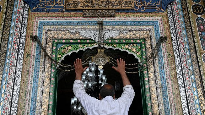 Seorang umat Muslim memegang rantai ikon keagamaan saat dia berdoa di Masjid Khanqah Shah, Srinagar, India, Rabu (13/4/2022). [TAUSEEF MUSTAFA / AFP]