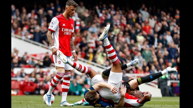 Bek Arsenal Ben White (kiri) melihat gelandang Manchester United Scott McTominay (tengah) berselisih dengan bek Arsenal Gabriel (kanan) saat pertandingan sepak bola Liga Premier Inggris antara Arsenal dan Manchester United di Stadion Emirates, London, Inggris, Sabtu (23/4/2022). [Ian Kington / IKIMAGES / AFP]
