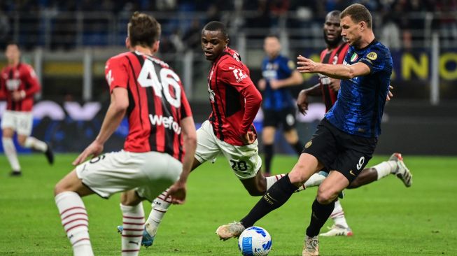 Penyerang Inter Milan Edin Dzeko (kanan) menantang bek AC Milan Pierre Kalulu (tengah) saat pertandingan sepak bola Serie A Liga Italia antara Inter Milan dan AS Roma di stadion San Siro, Milan, Italia, Sabtu (23/4/2022). [MIGUEL MEDINA / AFP]