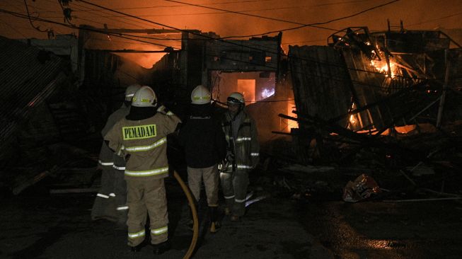 Sejumlah pemadam kebakaran memadamkan api yang membakar kios dan rumah di pasar Gembrong, Jatinegara, Jakarta Timur, Minggu (24/4/2022). [ANTARA FOTO/ Fakhri Hermansyah/pras]