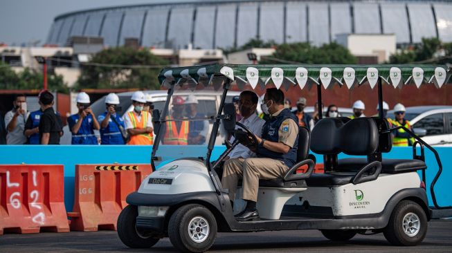 Presiden Joko Widodo (kiri) berbincang dengan Gubernur DKI Jakarta Anies Baswedan (kanan) seusai mengelilingi Sirkuit Formula E di Ancol, Jakarta Utara, Senin (25/4/2022). [ANTARA FOTO/Sigid Kurniawan]