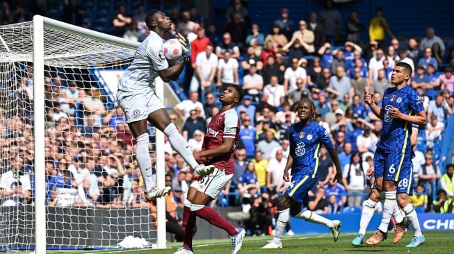 Penjaga gawang Chelsea Edouard Mendy (kiri) melompat untuk menangkap bola saat pertandingan sepak bola Liga Premier Inggris antara Chelsea dan West Ham United di Stadion Stamford Bridge, London, Inggris, Minggu (24/4/2022). [JUSTIN TALLIS / AFP]