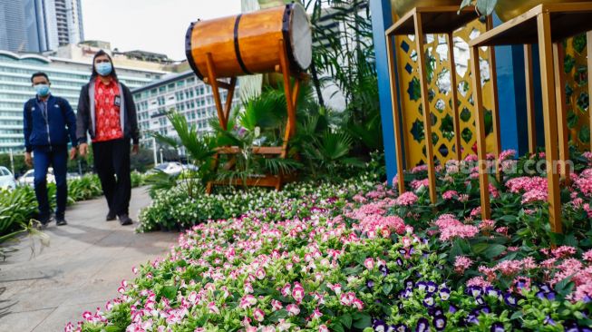 Warga melihat ornamen bernuansa lebaran yang terpasang di kawasan Bundaran HI, Jakarta Pusat, Selasa (26/4/2022). [Suara.com/Alfian Winanto]