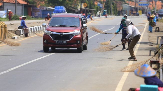 Sejumlah warga menunggu pengendara motor memberi sedekah dengan melempar uang di Jembatan Sewo, Jalur Pantura Sukra Indramayu, Jawa Barat, Senin (25/4/2022).  ANTARA FOTO/Dedhez Anggara
