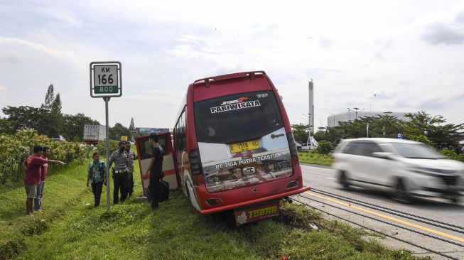 Sejumlah personel polisi melihat kondisi sebuah mini bus yang bernopol E 7506 KC usai mengalami kecelakaan tunggal di kilometer 166 Tol Palimanan-CIkampek, Jawa Barat, Selasa (26/4/2022).  ANTARA FOTO/M Risyal Hidayat
