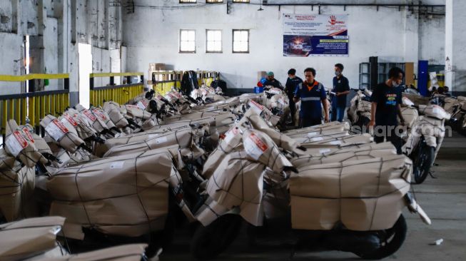 Petugas mengemas motor sebelum dikirim menggunakan kereta di Stasiun Kampung Bandan, Jakarta Utara, Selasa (26/4/2022). [Suara.com/Alfian Winanto]