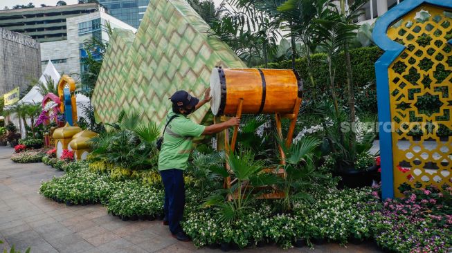 Petugas memasang hiasan bedug untuk ornamen bernuansa lebaran yang terpasang di kawasan Bundaran HI, Jakarta Pusat, Selasa (26/4/2022). [Suara.com/Alfian Winanto]