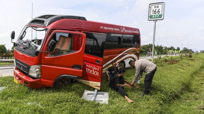 Sejumlah personel polisi melihat kondisi sebuah mini bus yang bernopol E 7506 KC usai mengalami kecelakaan tunggal di kilometer 166 Tol Palimanan-CIkampek, Jawa Barat, Selasa (26/4/2022).  ANTARA FOTO/M Risyal Hidayat
