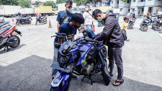 Petugas mengecek keadaan sepeda motor sebelum dikemas dan dikirim menggunakan kereta di Stasiun Kampung Bandan, Jakarta Utara, Selasa (26/4/2022). [Suara.com/Alfian Winanto]