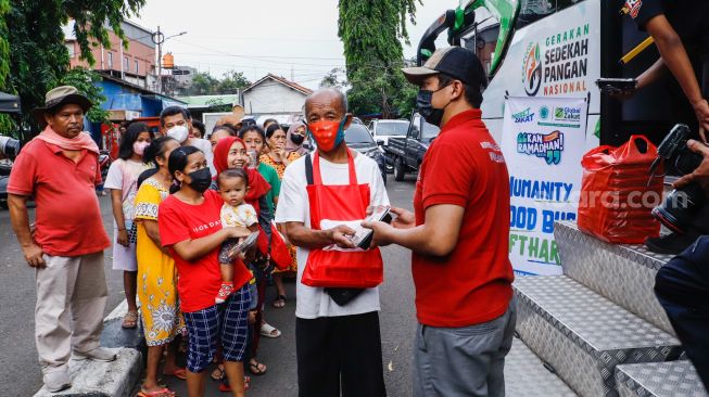 Petugas membagikan bantuan makanan kepada warga didepan Humanity Food Bus di Cipete Utara, Jakarta Selatan, Jumat (29/4/2022). [Suara.com/Alfian Winanto]