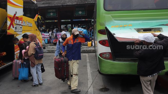 Penumpang memasukkan barang bawaan ke dalam bagasi bus di Terminal Kampung Rambutan, Jakarta, Sabtu (30/4/2022). [Suara.com/Angga Budhiyanto]