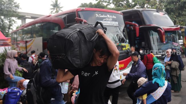 Calon penumpang membawa barang bawaan saat menunggu kedatangan bus di Terminal Kampung Rambutan, Jakarta, Sabtu (30/4/2022). [Suara.com/Angga Budhiyanto]