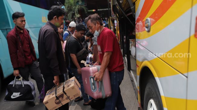 Penumpang memasukkan barang bawaan ke dalam bagasi bus di Terminal Kampung Rambutan, Jakarta, Sabtu (30/4/2022). [Suara.com/Angga Budhiyanto]